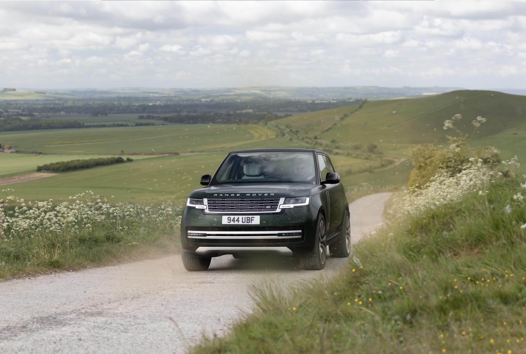 英国の丘陵地帯に伸びる未舗装路を走るRANGE ROVER ELECTRICのフロントビュー